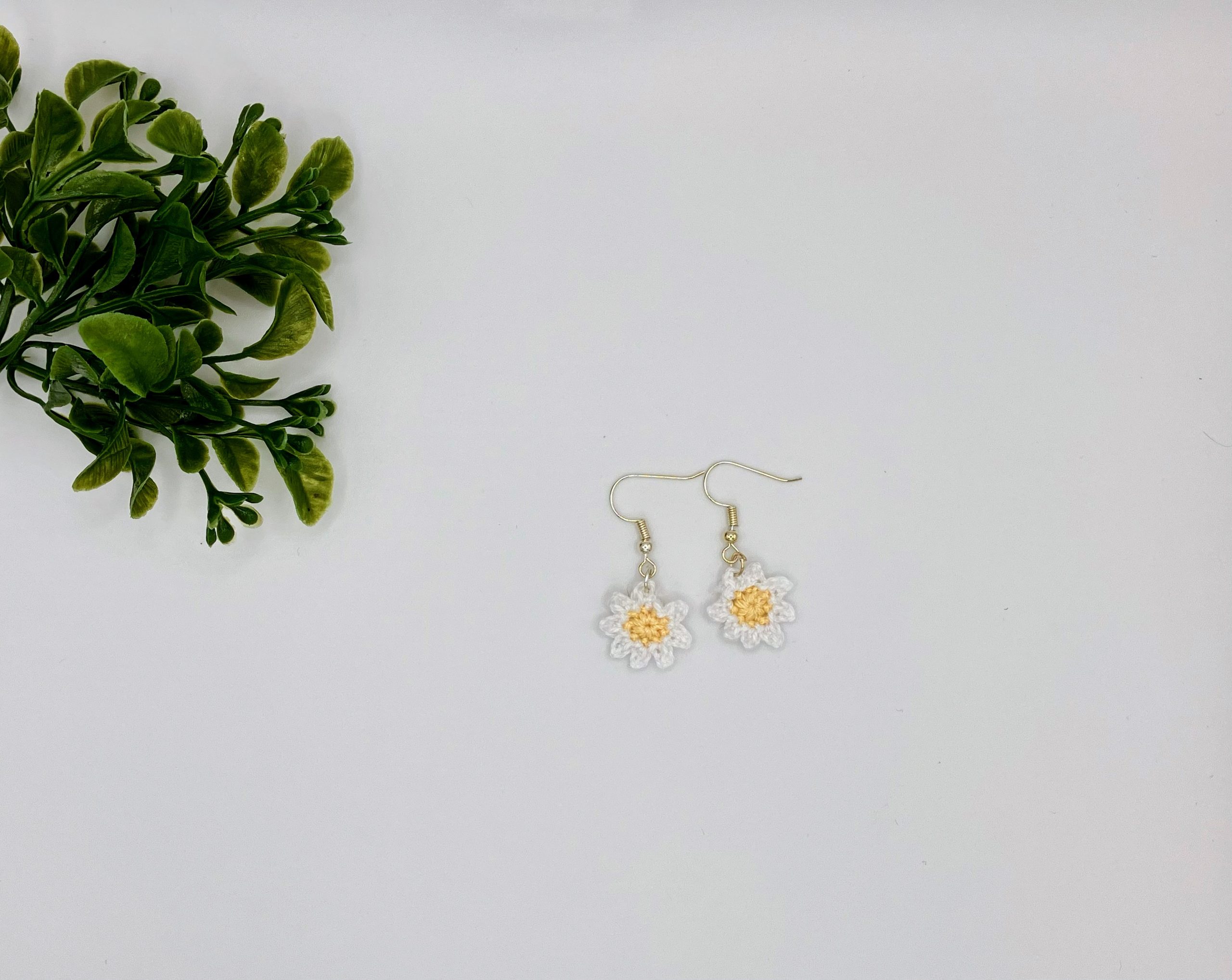 White daisy earrings laying on white backdrop