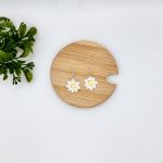 Crochet daisy earrings laying flat on a wood surface