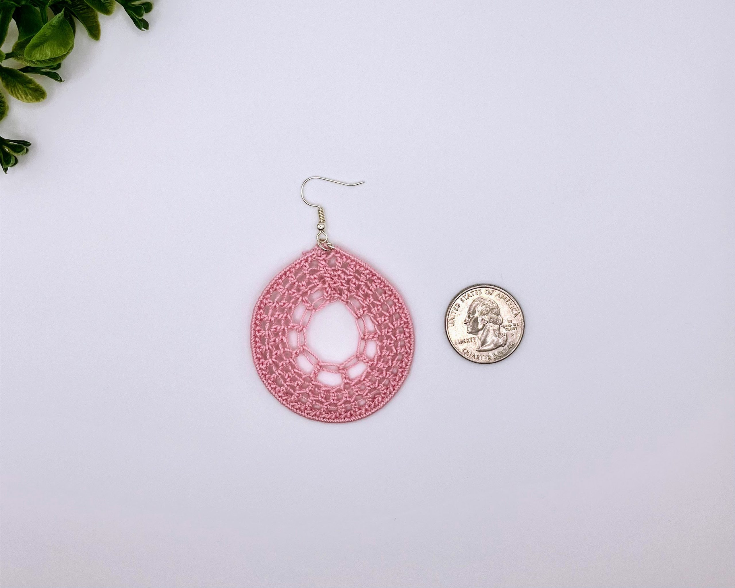 Reference image of a light pink crocheted dream catcher earring next to a quarter.