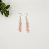 Pair of beaded dangle earrings lying on a white backdrop