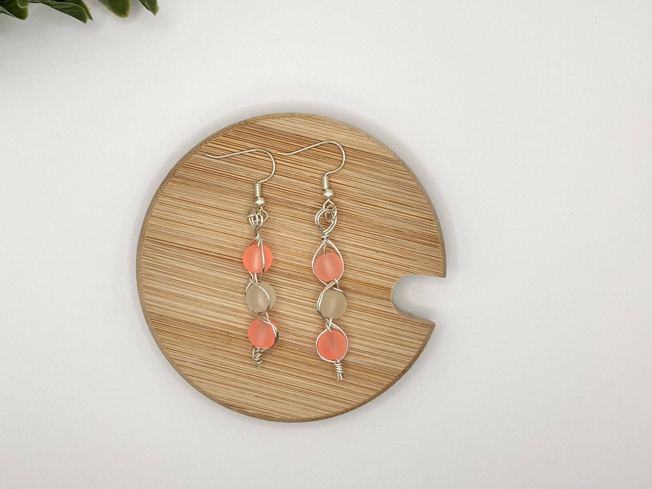 Pair of beaded dangle earrings laying on a wood coaster