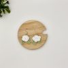 Crochet white rose earrings laying flat on a wood backdrop