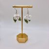 Crochet white rose earrings hanging on a gold earring stand