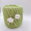 White crochet rose earrings hanging on a ball of green yarn
