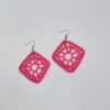 Crochet pink diamond shaped earrings laying next to each other on a white backdrop