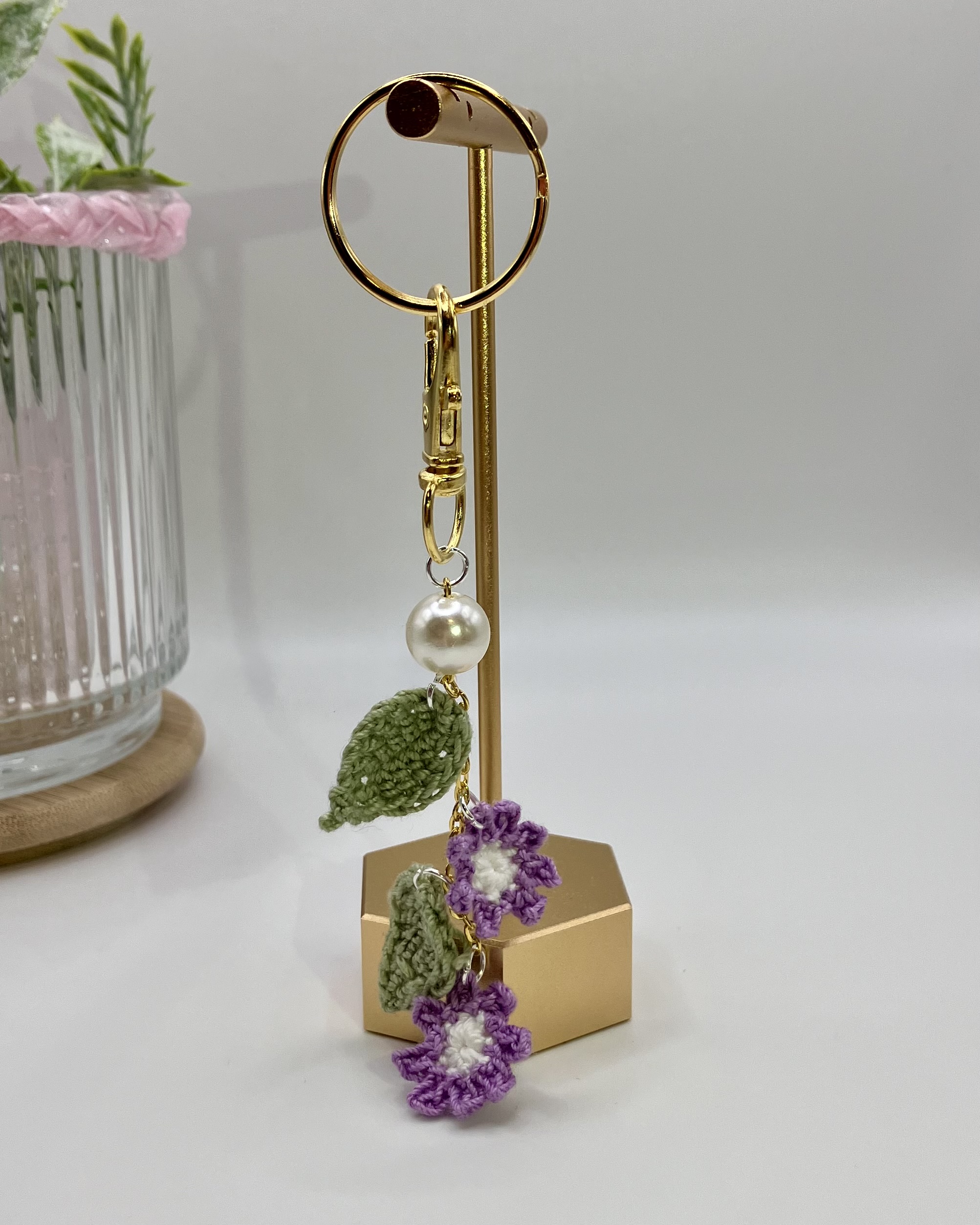 Crochet purple flower bag charm hanging on a gold hook