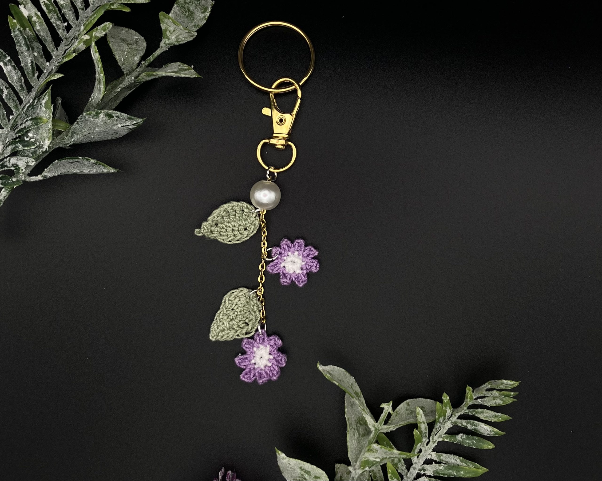 Crochet purple flower bag charm on a black backdrop