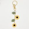 Crochet handmade sunflower bag charm, on a gold chain, with leaves, two flowers, pearl accent