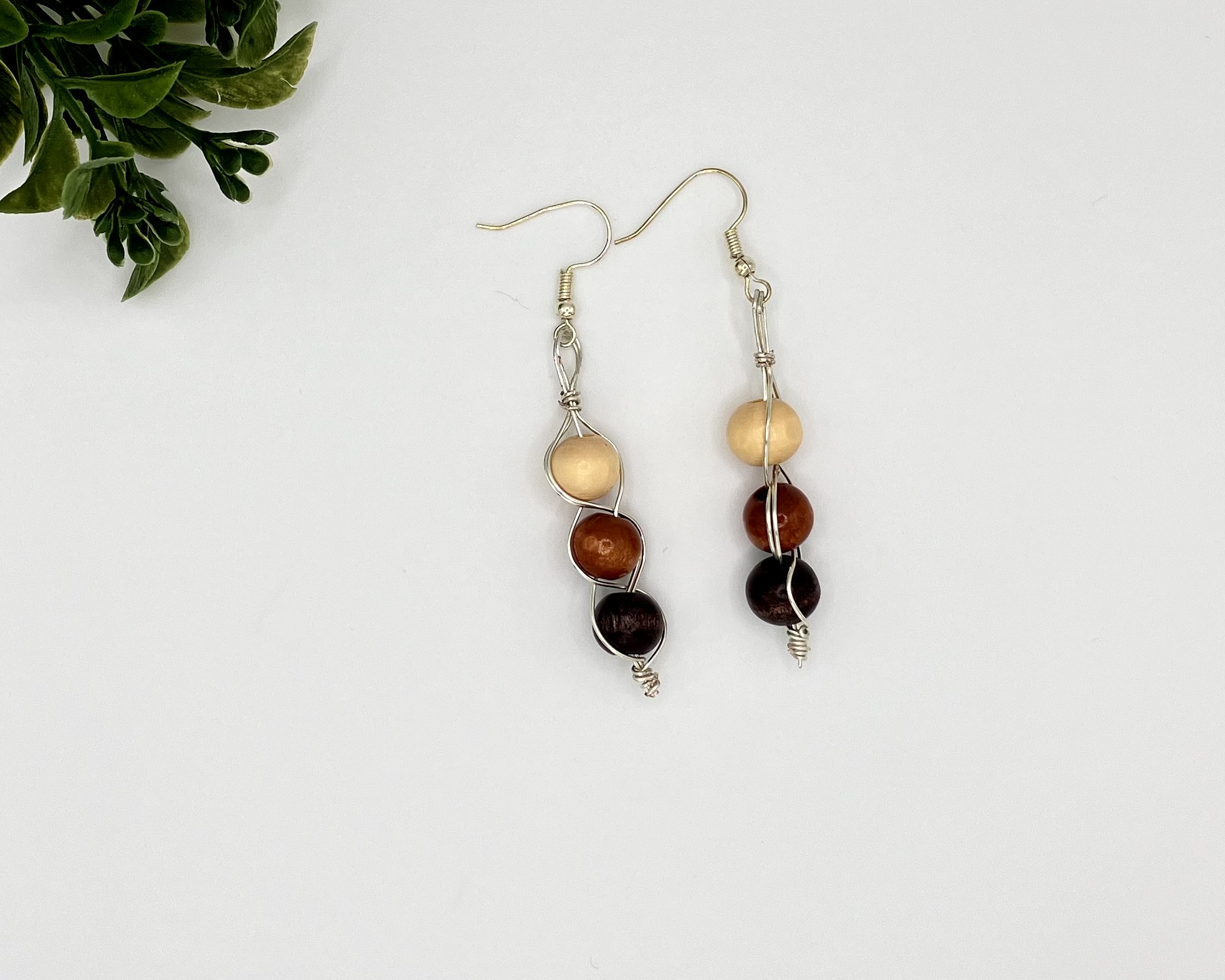 Wood beaded dangle earrings laying next to each other on a white backdrop