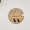 Wood beaded dangle earrings laying on a wood coaster