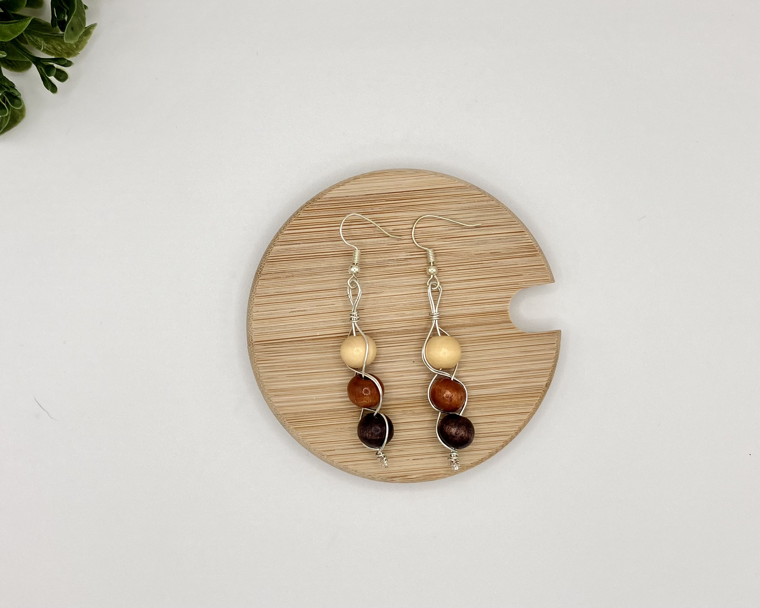 Wood beaded dangle earrings laying on a wood coaster