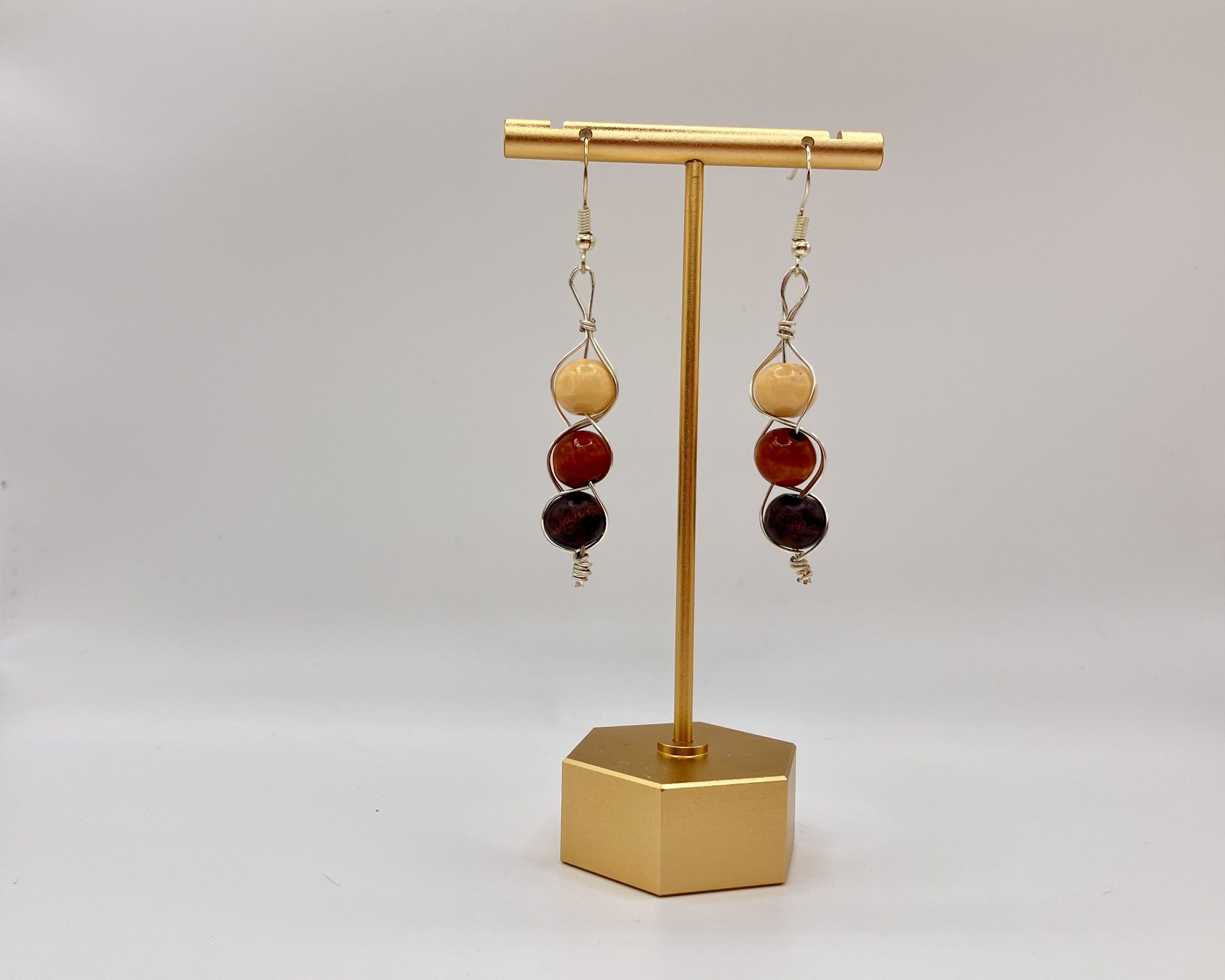 Wood beaded dangle earrings hanging on a gold earring stand