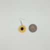 Crochet sunflower earring laying next to a quarter for reference