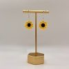 Crochet sunflower earrings hanging on a gold earrings stand