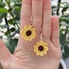 Crochet sunflower earrings in a hand for reference