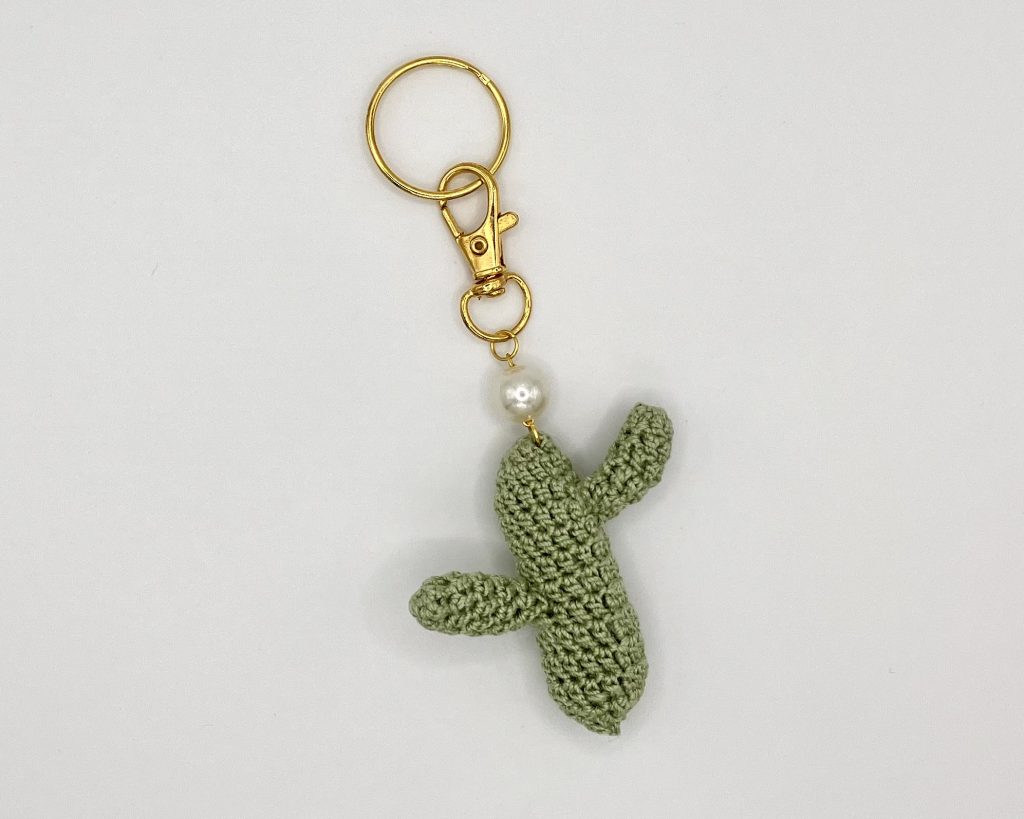 Crocheted green cactus with pearl accent on a gold key ring