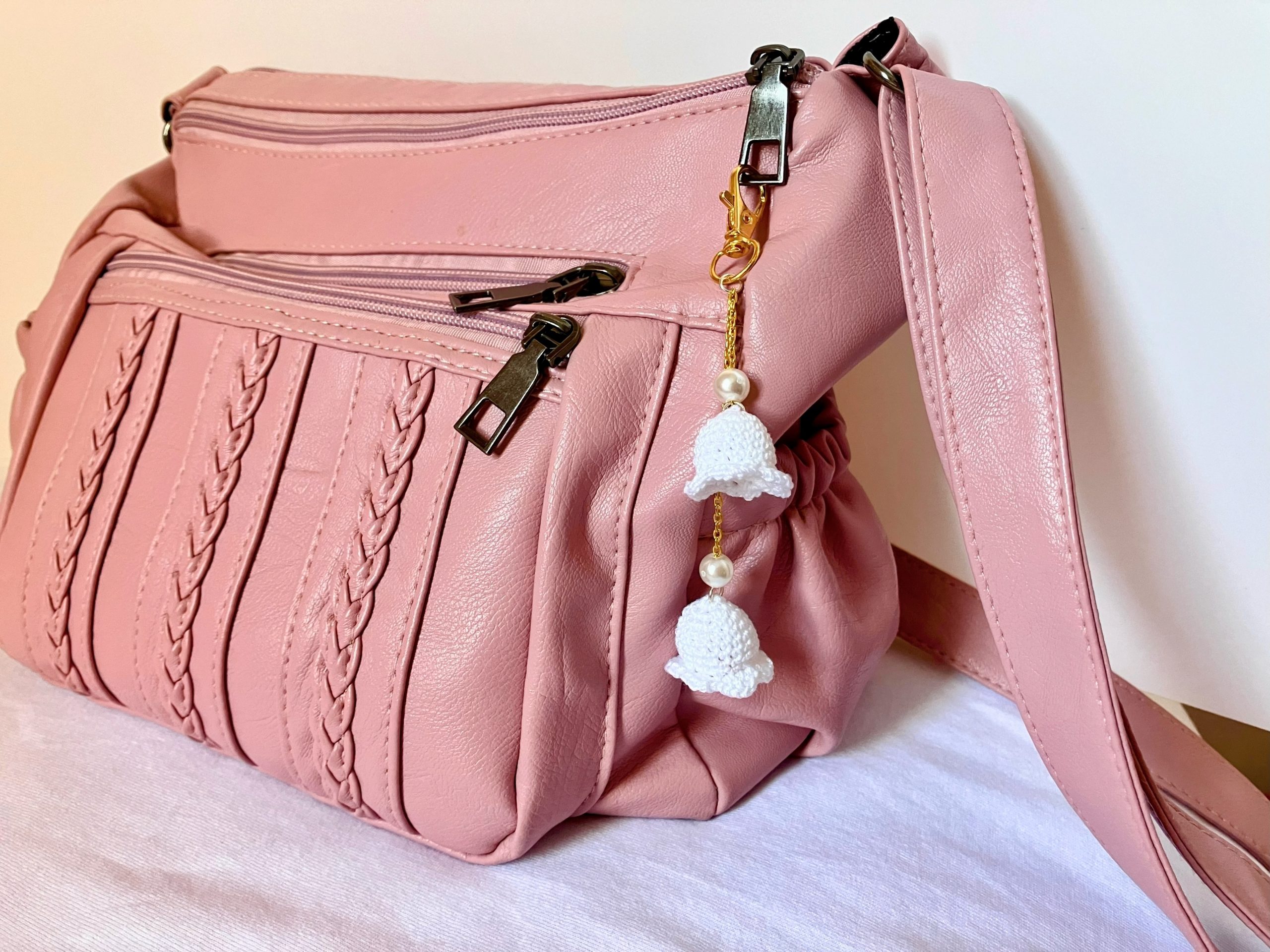 Lily bag charm with pearls on a gold chain displayed on a pink purse