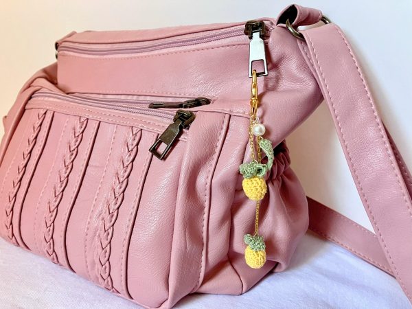 Pineapple bag charm hanging on a pink bag