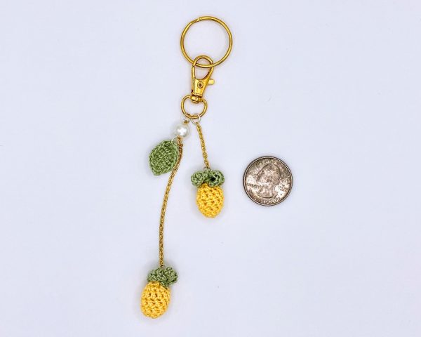 Pineapple bag charm next to a quarter for size reference