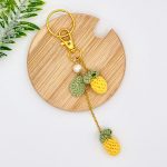 Pineapple bag charm with laying on a brown coaster