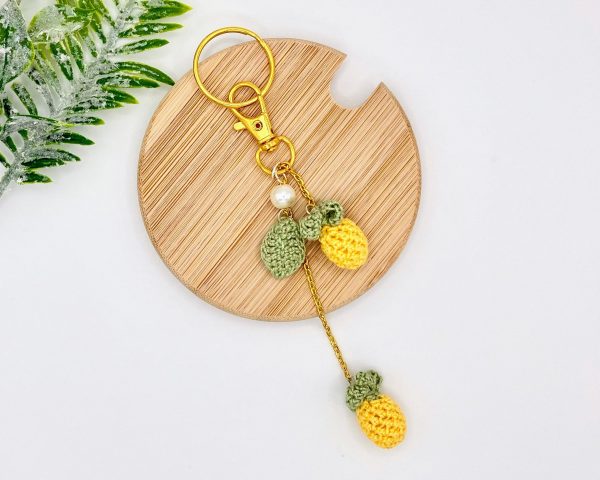 Pineapple bag charm with laying on a brown coaster