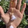 Lily bag charm with pearls on a gold chain, in a hand for reference