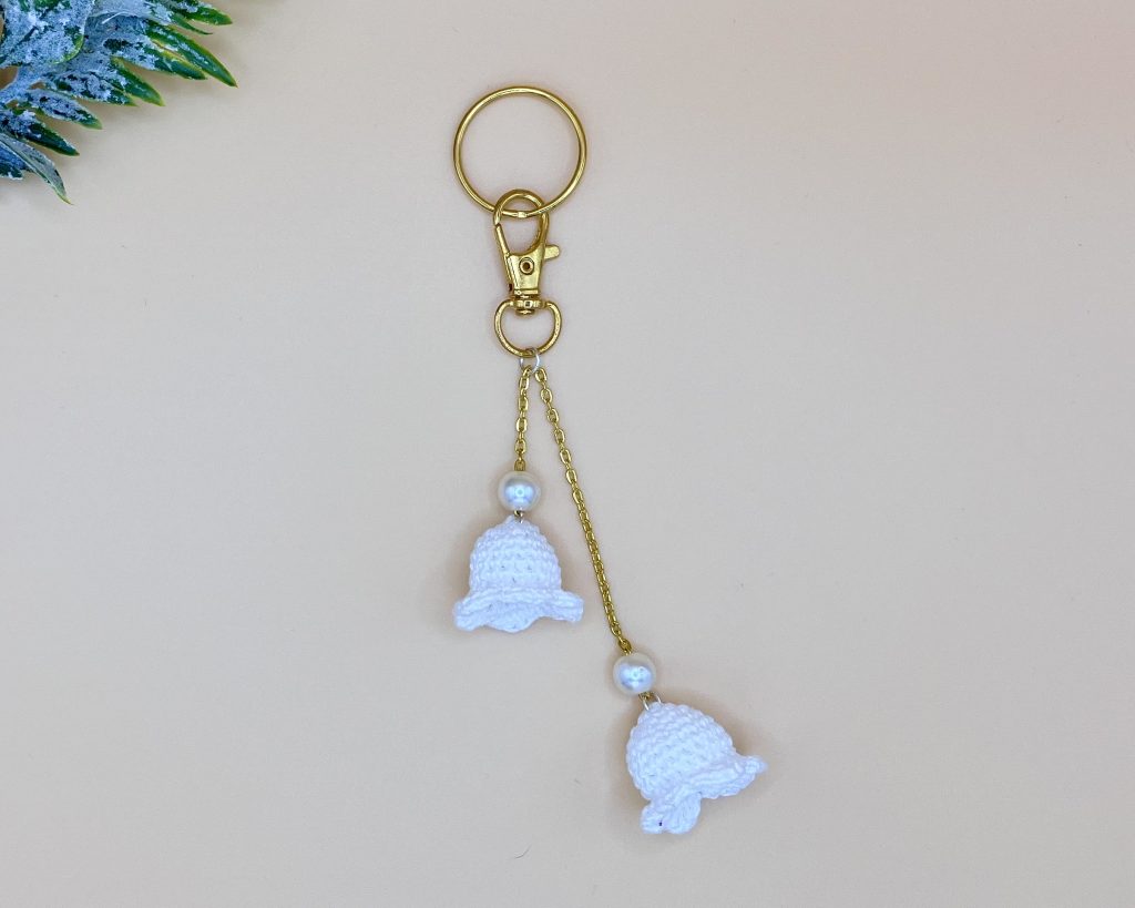 Lily of the valley bag charm on a gold chain with snap hook and key ring, and a gold pearl