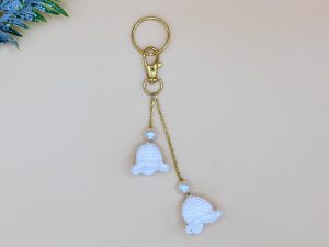 Lily of the valley bag charm on a gold chain with snap hook and key ring, and a gold pearl