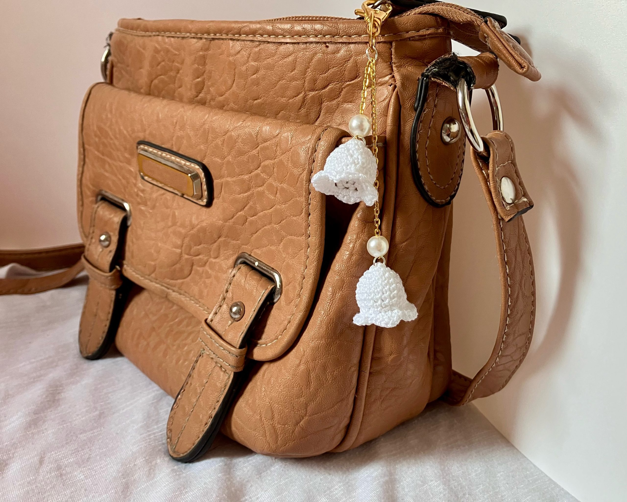 lily bag charm with pearls on a gold chain displayed on a bag