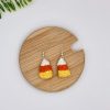 Crochet candy corn earrings laying flat on a wood backdrop