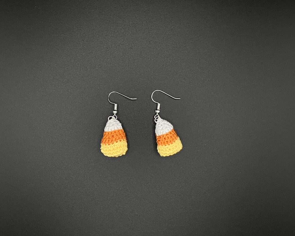 Crochet candy corn earrings on a black backdrop
