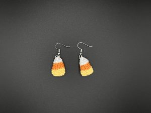 Crochet candy corn earrings on a black backdrop