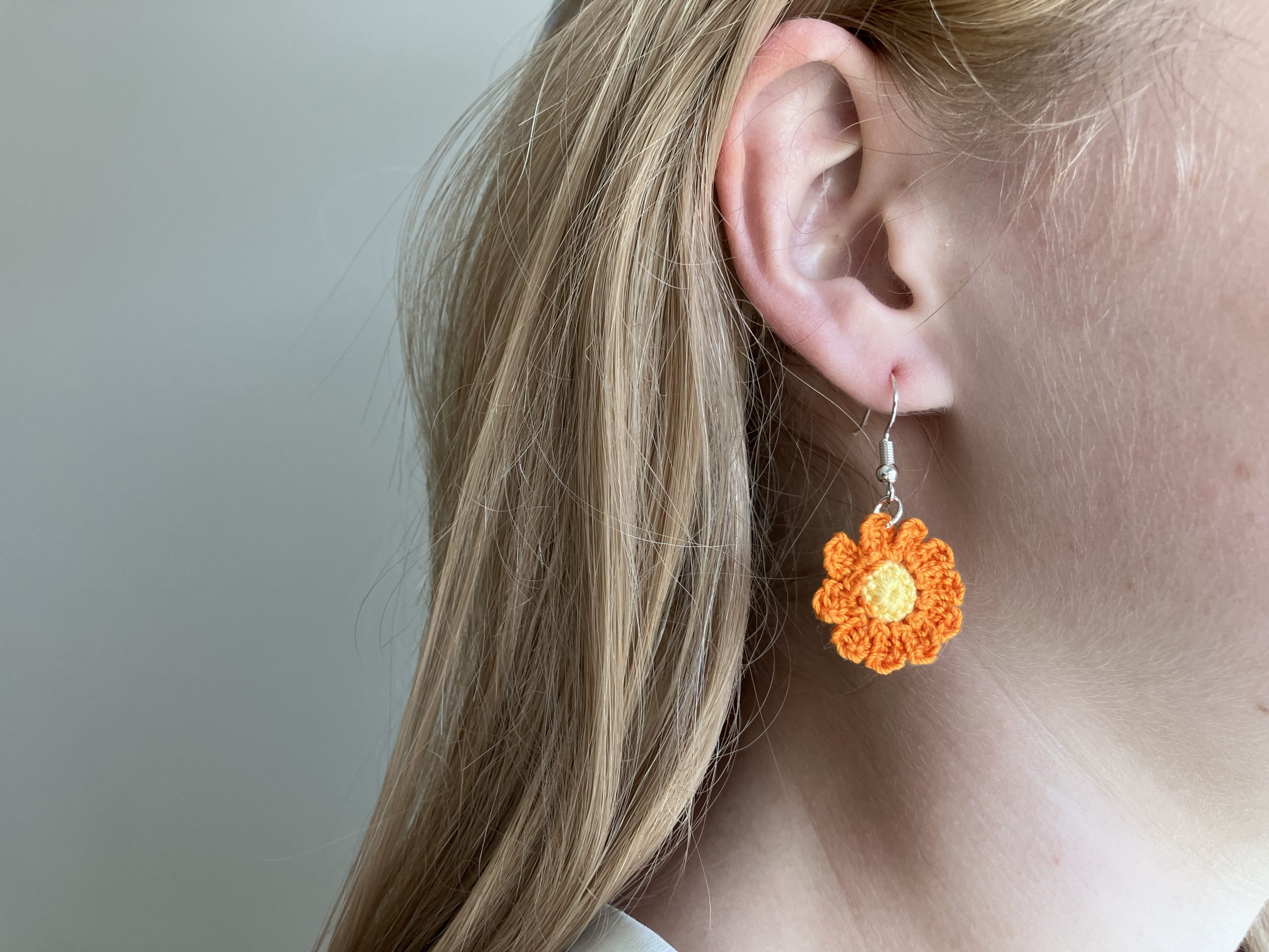 Model wearing a orange crochet flower earring