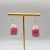 Crocheted pink candy corn earrings handing on a gold earring stand