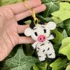 Handmade crochet cow keychain displayed against a lush plant backdrop, crafted with black and white cotton yarn, perfect for nature-inspired accessories