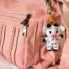 Handmade crochet cow bag charm attached to a pink purse, featuring black and white cotton yarn, perfect for adding a cute accessory to everyday bags.