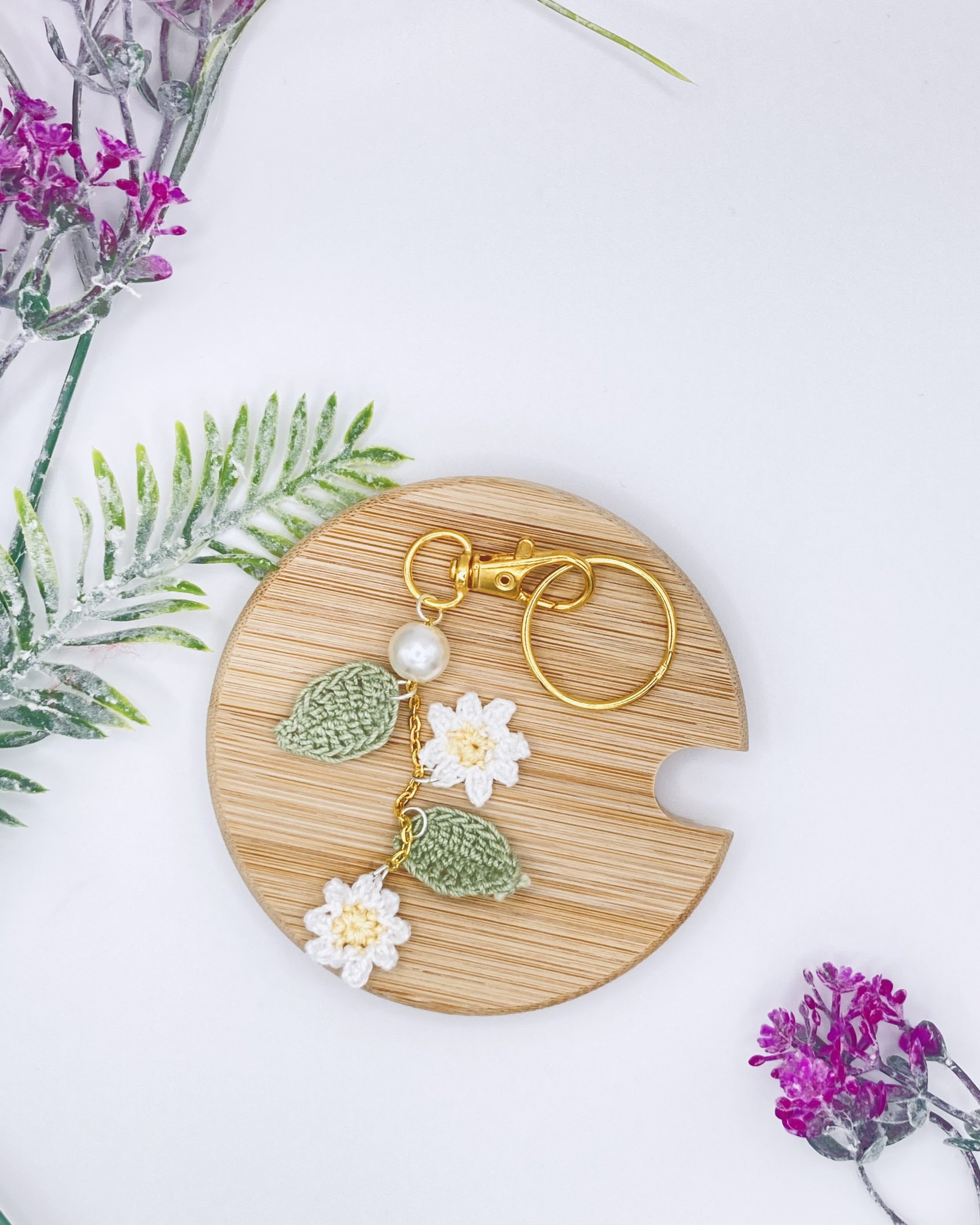 A crochet thread daisy purse charm displayed against a wood background