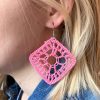 A reference image of a model wearing crochet pink diamond shaped earrings