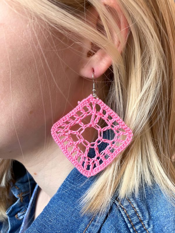 A reference image of a model wearing crochet pink diamond shaped earrings