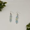 Sea blue and white beaded dangle earrings laying flat on a white Backdrop