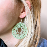 A model wearing crochet green dream catcher earrings