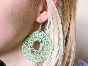 A model wearing crochet green dream catcher earrings