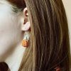 A model wearing crochet pumpkin earrings