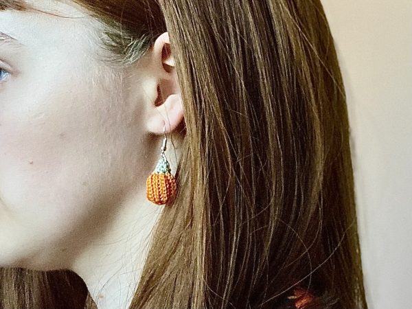 A model wearing crochet pumpkin earrings