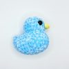 Blue crochet duck plushie laying on its side
