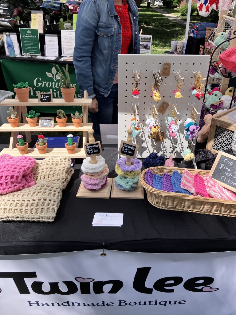 Handmade crochet products on display at Twin Lee booth, including keychains, scrunchies, and plush toys.
