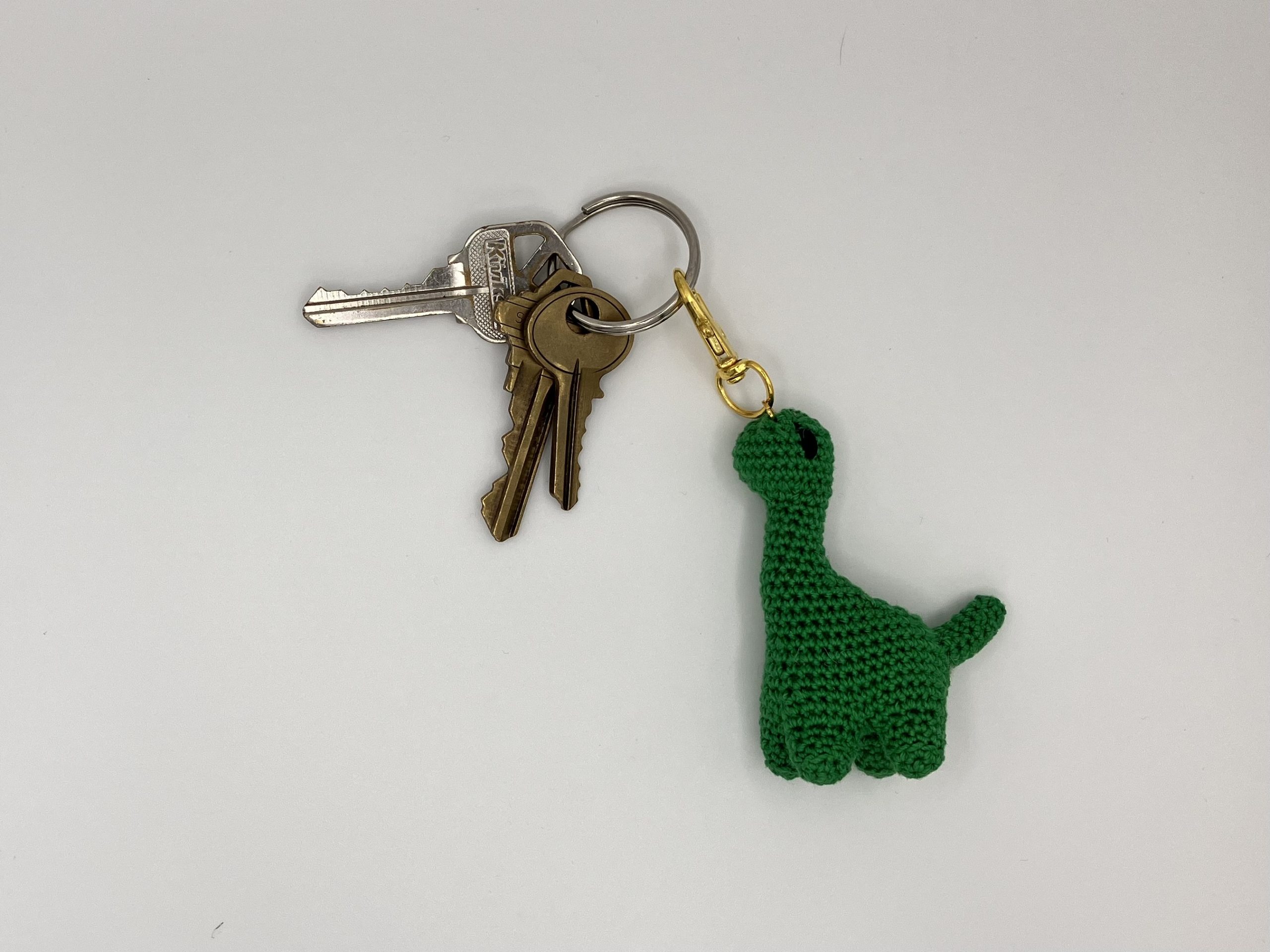 Green dinosaur keychain on a keyring of keys