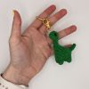 Green crochet Dinosaur keychain in a hand for size reference