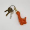 Orange crochet dinosaur keychain on a keyring