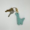 Blue crochet dinosaur keychain on a keyring